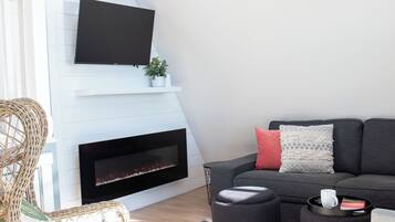 A modern living room with a fireplace, a sofa, a coffee table, and a TV mounted on the wall.