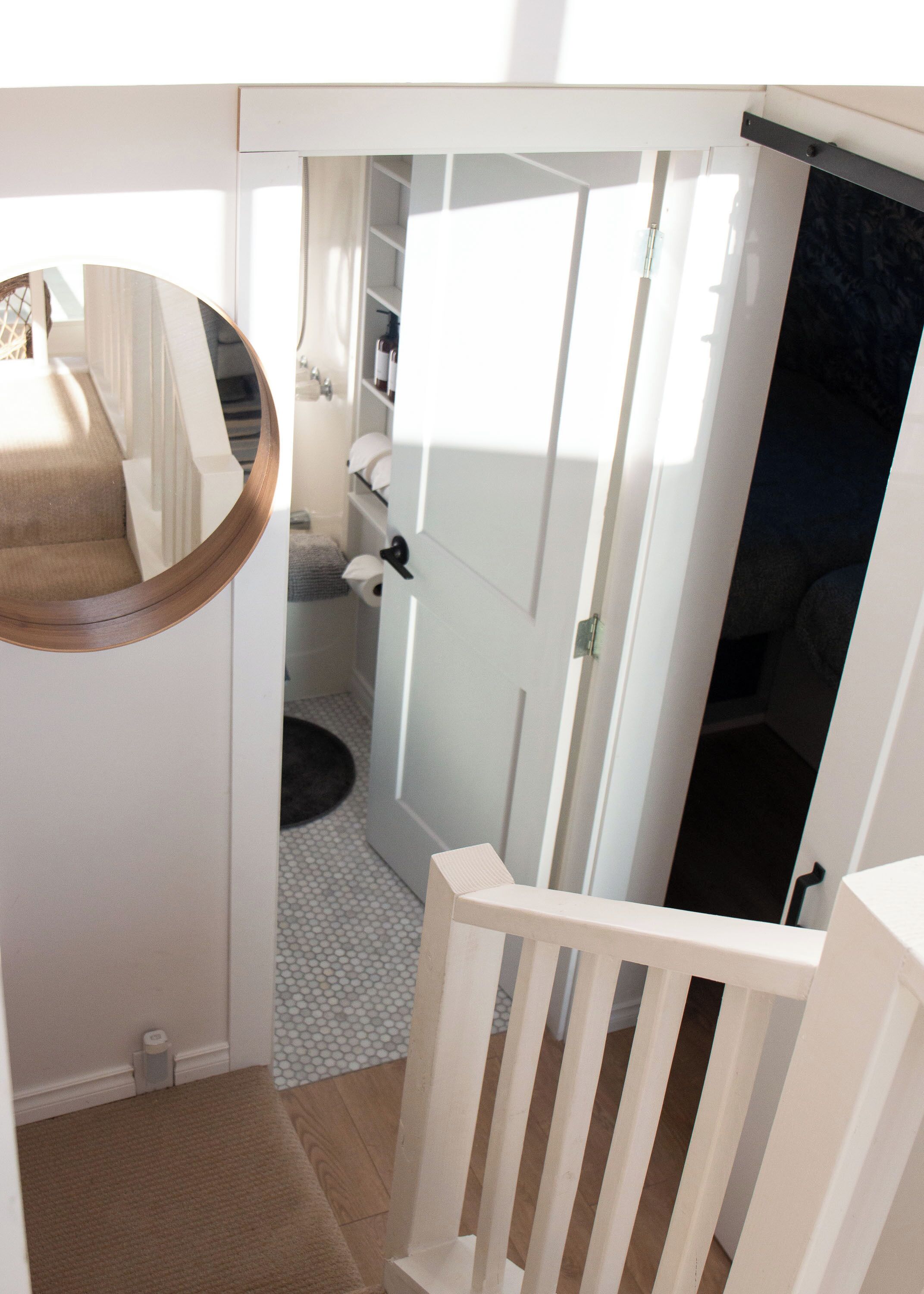A staircase with a white railing leading to a room with a closet and a door.