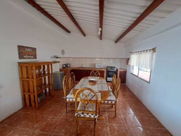 Un comedor con una mesa y sillas de madera, una cocina al fondo y un cartel que dice 'Thank You' en la pared.