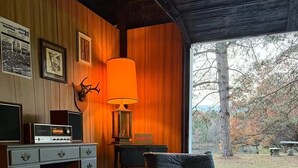 Une pièce chaleureuse avec un mur en bois, un bureau avec un ordinateur, une lampe et une chaise.