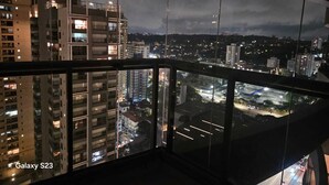 Een nachtzicht vanaf een balkon met een stadsgezicht op de achtergrond.