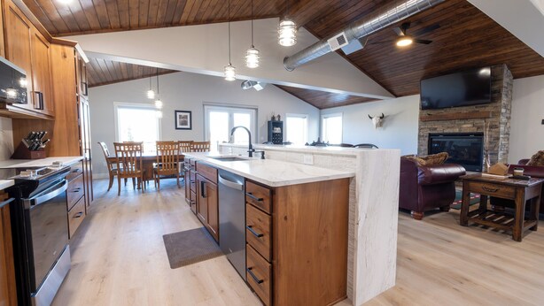 Une cuisine spacieuse avec des meubles en bois, un grand îlot central et une cheminée en pierre.