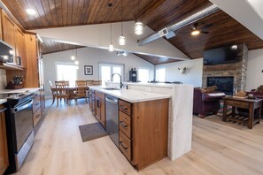 Una cocina amplia con armarios de madera, una isla grande y una chimenea de piedra.