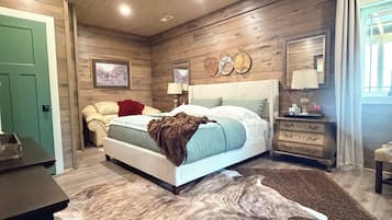 Un dormitorio con cama, mesita de noche, cómoda, puerta verde y techo de madera.