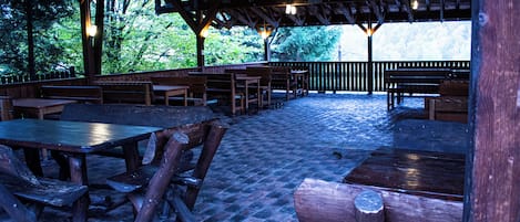 An outdoor wooden deck with benches and tables, surrounded by trees.