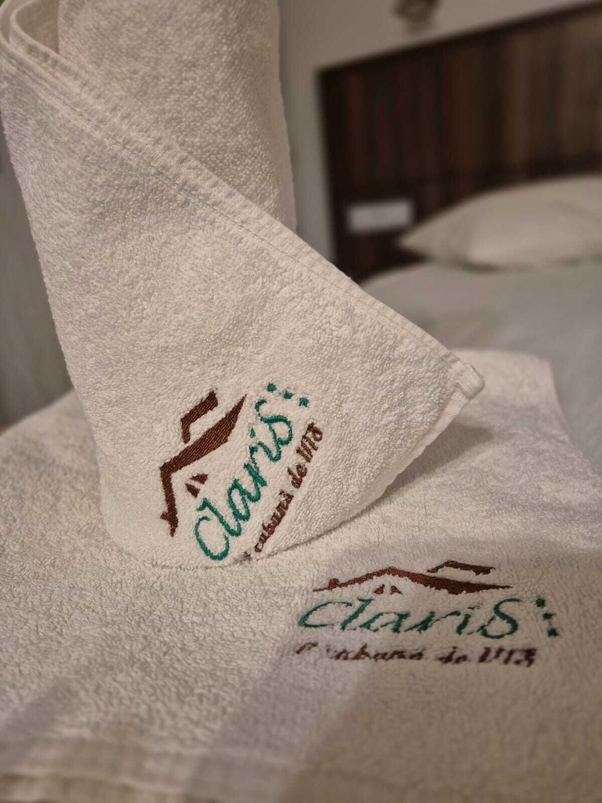 Une serviette ornée d’une broderie avec les inscriptions « Claris » et « Claris de Lima », indiquant qu’il s’agit d’un hôtel ou d’un établissement.