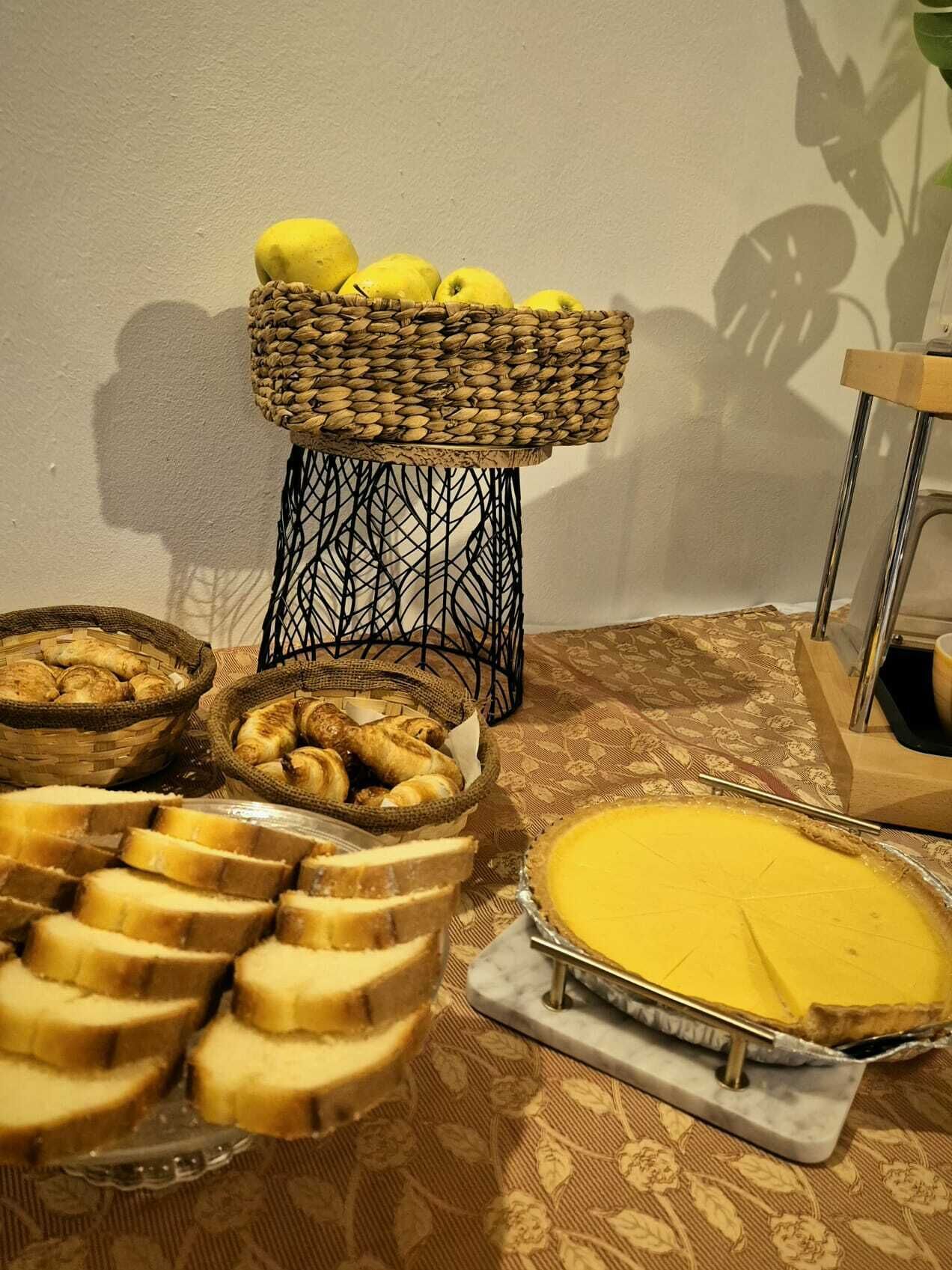 A buffet table with various food items including bread, pastries, and a pie.