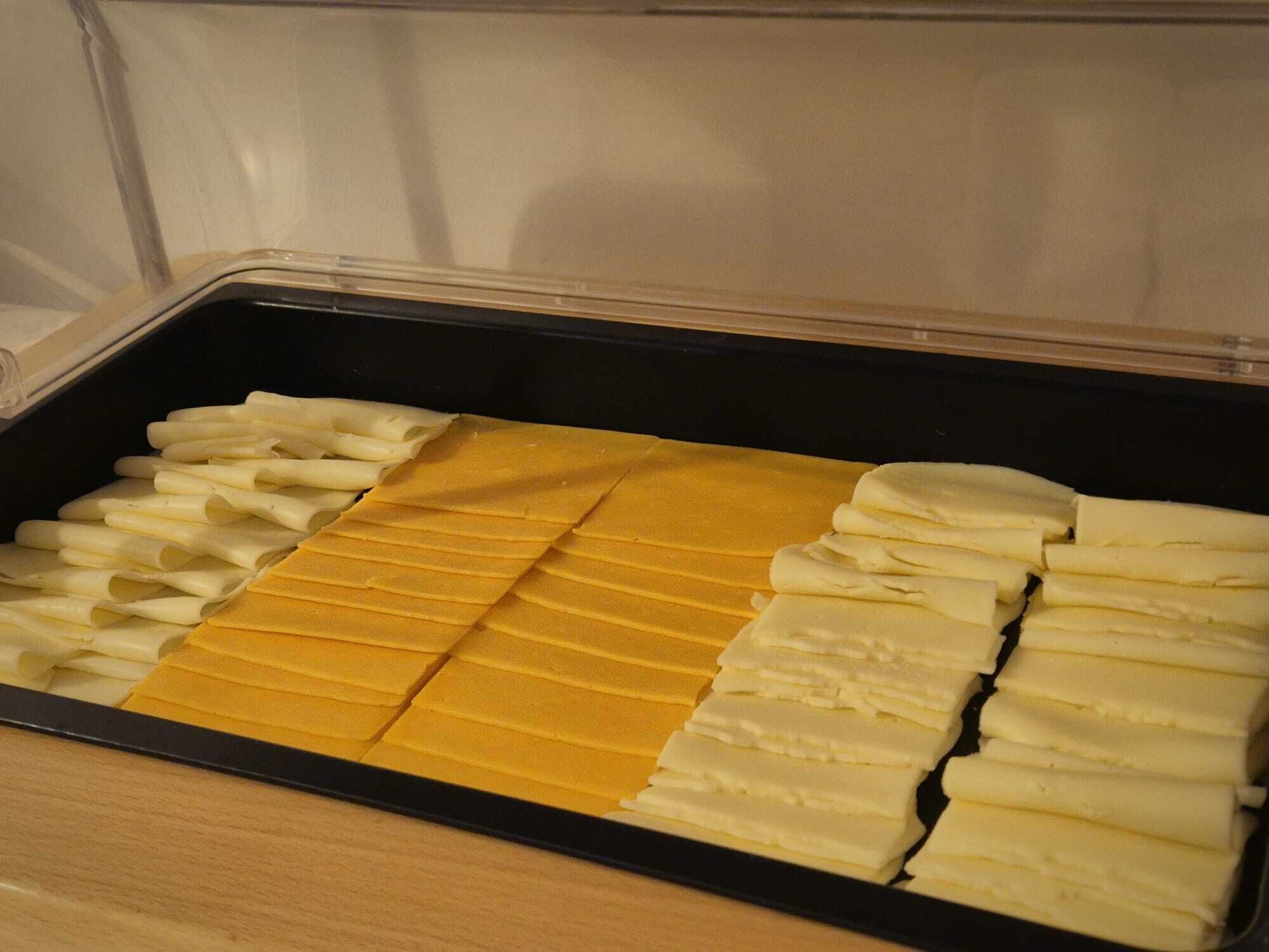 Ein Lagerbehälter mit ordentlich angeordneten Lebensmitteln, darunter gelbe und weiße Scheiben, vermutlich Käse oder ähnliche Produkte.