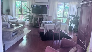 Una sala de estar con sofá, mesa de centro, televisor y comedor con sillas y mesa.