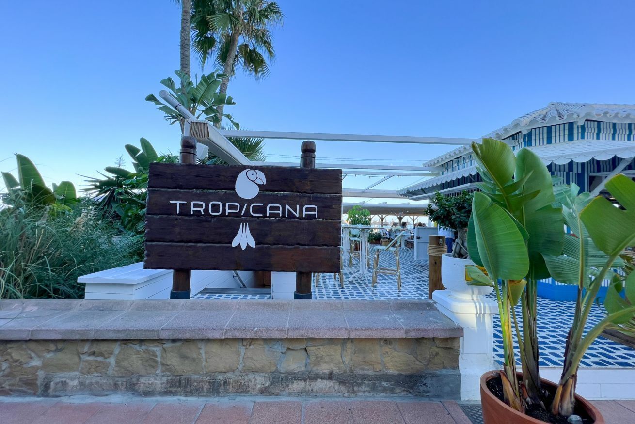 Et træskilt med navnet "TROP/CANA" og en svane-logo, der angiver et hotel eller resort.