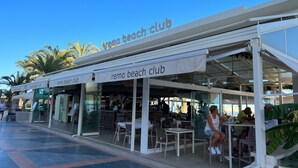 A beach club with outdoor seating and palm trees in the background. - Carihuela Beach studio, 2nd line of the beach (Torremolinos)