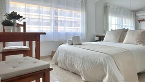 A bedroom with a large bed, a wooden chair, a small table, and a potted plant. - Carihuela Beach studio, 2nd line of the beach (Torremolinos)