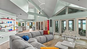 A modern living room with a grey sectional sofa, a coffee table, and a dining area with a patterned rug. - Waterfront Stay w/ Canoes, Deck, Game Room & Lake Views Near Mooresville Renwick Cove by Avantstay (Mooresville)