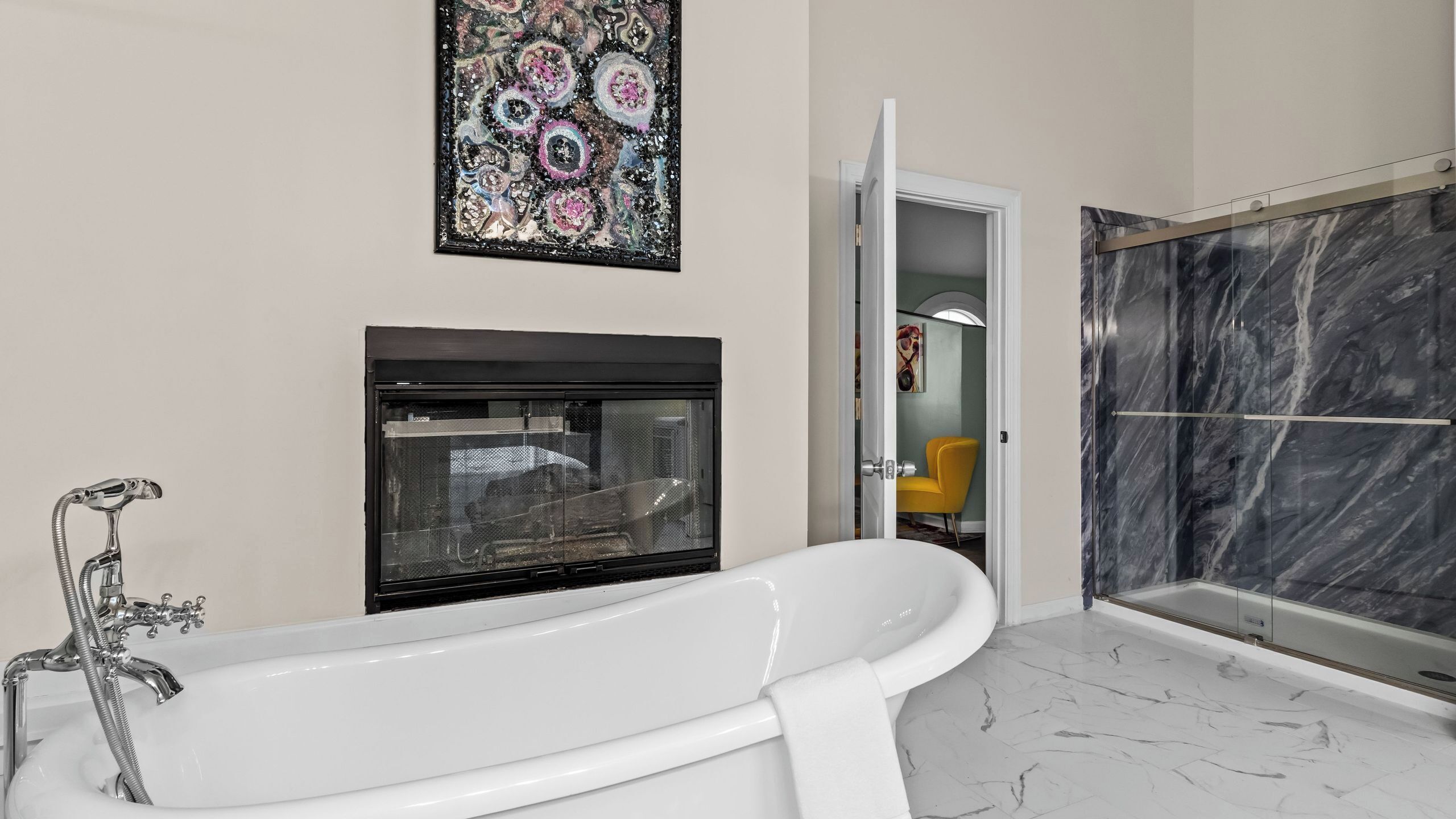 A bathroom with a freestanding bathtub, a fireplace, and a marble shower enclosure.