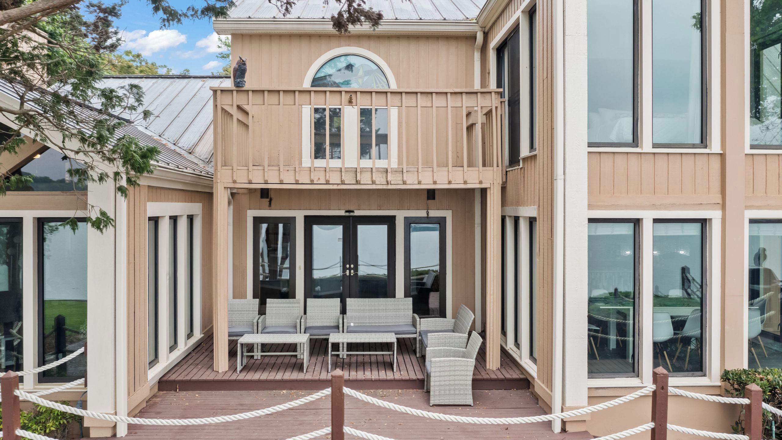 A two-story building with a balcony, large windows, and outdoor seating.