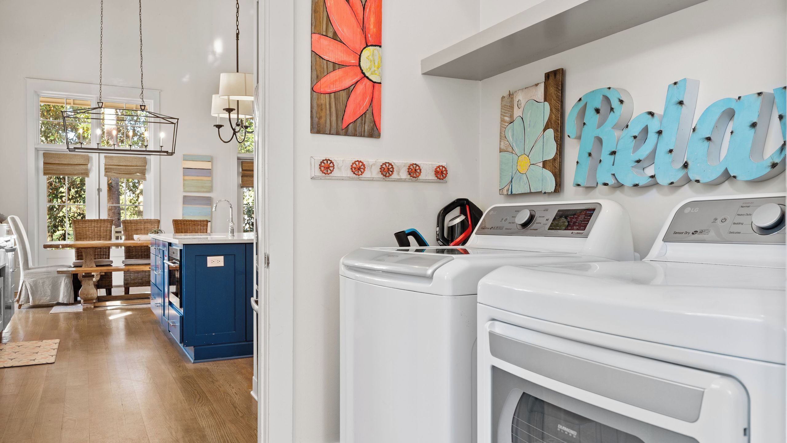 A laundry area with two white washing machines, a hanging rack, and a wall-mounted drying rack.