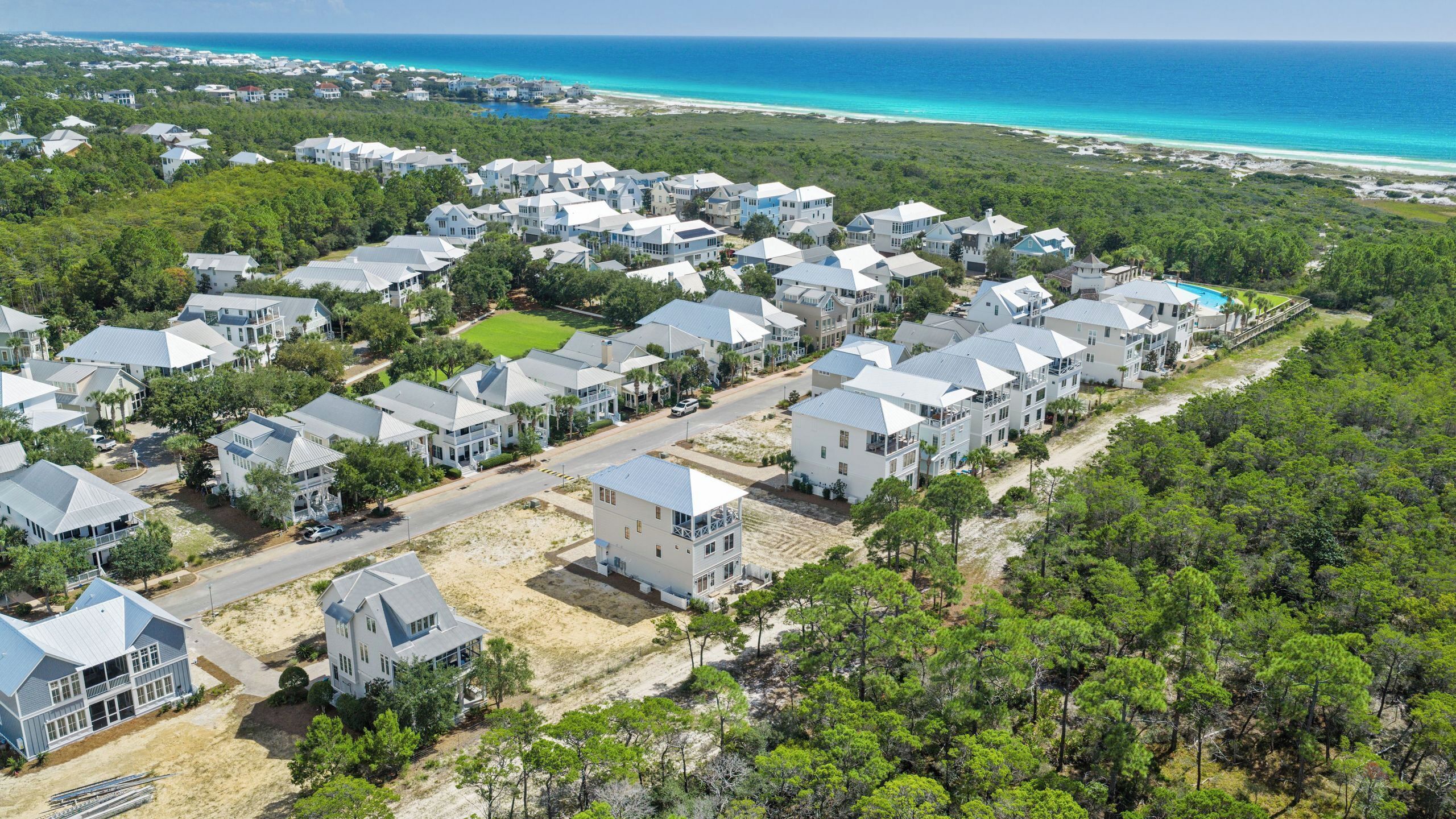 An aerial view of a coastal residential area with houses, a beach, and a clear sky.