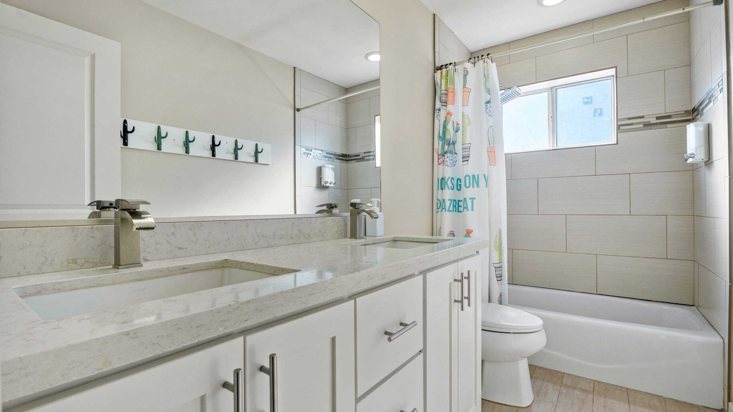 Un baño moderno con tocador doble, inodoro y bañera.