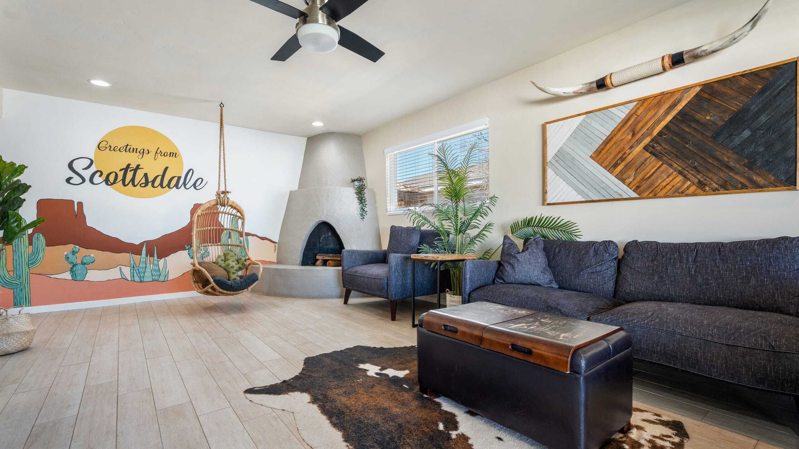 A modern living room with a sofa, a hanging chair, a fireplace, and a wall mural.