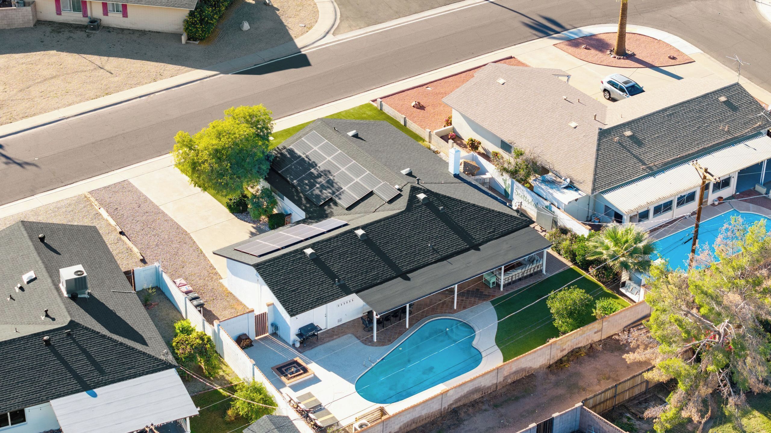 A residential property with a swimming pool, solar panels, and a covered outdoor seating area.