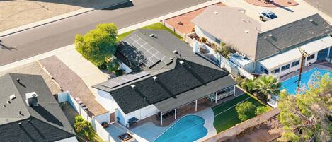 A residential property with a swimming pool, solar panels, and a covered outdoor seating area.
