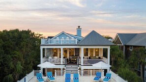 A two-story house with a balcony, outdoor seating area, and a staircase leading to the entrance. - Beachside Stay With Pool, Two Decks, Rooftop Lounge & Steps to Front Beach IOP Beachhouse by Avantstay (Isle of Palms)