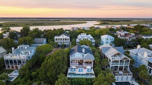 A residential area with houses, a swimming pool, and a river in the background. - Beachside Stay With Pool, Two Decks, Rooftop Lounge & Steps to Front Beach IOP Beachhouse by Avantstay (Isle of Palms)