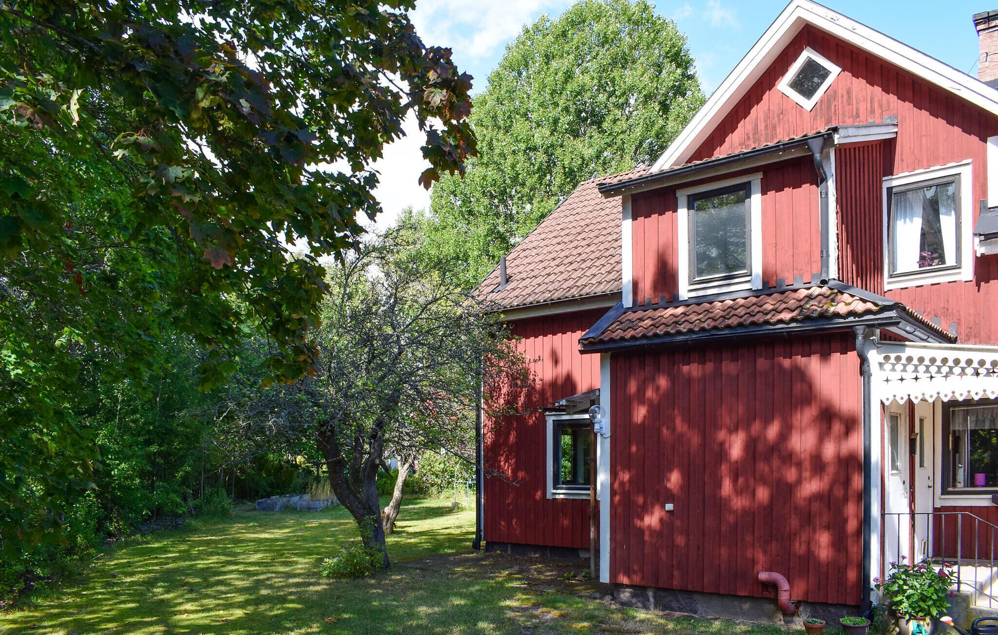 Een rood houten huis met een pannendak, een zichtbare schoorsteen en een klein portaal met potplanten.