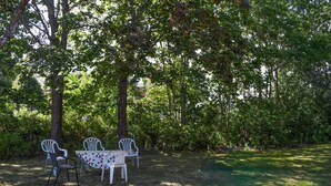 Un espace extérieur aménagé avec une table et des chaises, entouré d’arbres.