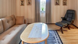 Un salon avec un canapé, une table avec un set de table, une chaise et des tableaux encadrés accrochés au mur.