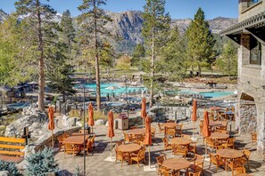 Un área de piscina con varias piscinas, mobiliario exterior y un paisaje montañoso.