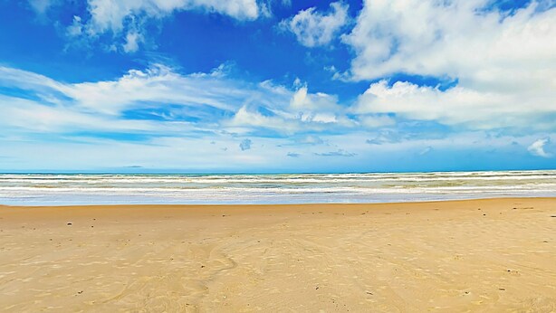 A beach with a clear sky and ocean waves.
