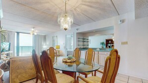A dining area with a glass table, wooden chairs, and a chandelier.
