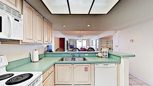 A kitchen with a central island, a microwave, a stove, and a dishwasher.