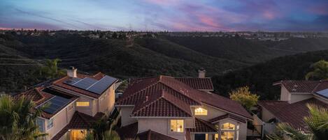 Residential houses with solar panels, surrounded by hills.
