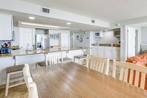 A kitchen with white cabinets, a wooden dining table, and chairs. - Beachfront, Stunning Views: Suntide III - Unit 403 (South Padre Island)