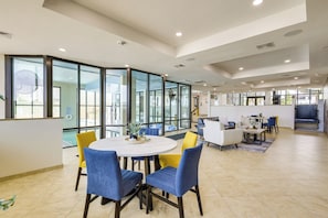 A modern hotel lobby with a round dining table, blue and yellow chairs, a sofa, and a fireplace. - Beachfront, Stunning Views: Suntide III - Unit 403 (South Padre Island)