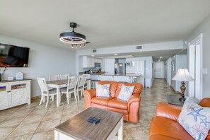 A living room with a sofa, coffee table, and TV. There is a kitchen in the background. - Beachfront, Stunning Views: Suntide III - Unit 403 (South Padre Island)