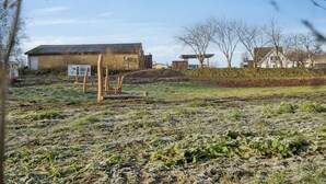A rural landscape with a building, a wooden structure, and a signboard.