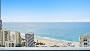 Paisagem costeira com edifícios altos, uma praia e um céu azul límpido.