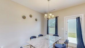 A dining area with a marble table, six chairs, a chandelier, and decorative wall art. - Remote-Work Ready! 'Serenity House' in Goldsboro (Goldsboro)