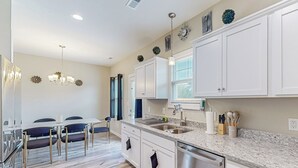 A modern kitchen with white cabinets, a granite countertop, stainless steel appliances, and a dining area with a table and chairs. - Remote-Work Ready! 'Serenity House' in Goldsboro (Goldsboro)