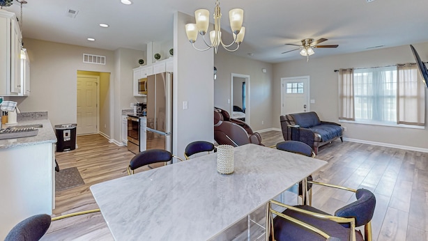 A modern kitchen with a dining area, a ceiling fan, and a large window. - Remote-Work Ready! 'Serenity House' in Goldsboro (Goldsboro)
