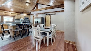 Une cuisine spacieuse avec des meubles en bois, un îlot central et un coin repas doté de chaises blanches.