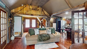 A cozy living room with a sofa, wooden floors, and a dining area with chairs and a table. - Walk to Trails & Fishing Spots! Lake Ozark Escape (Lake Ozark)
