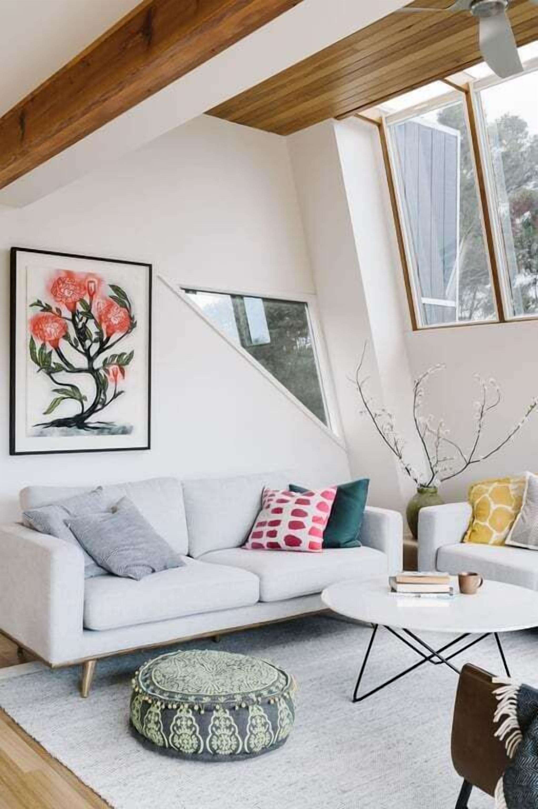 A modern living room with a white sofa, a round coffee table, and a painting of flowers on the wall.