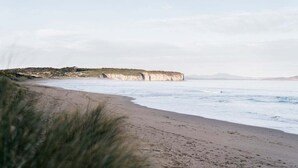 Una playa costera con acantilados y una orilla arenosa.