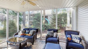 A covered porch with wicker furniture and a glass table, overlooking a backyard with trees and a house. - Leaf Peeping & Skiing Nearby! Poconos Getaway (Albrightsville)