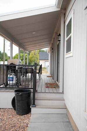 A covered outdoor patio with a table and chairs, a gas canister, and a trash bin. - Enjoyable 4-bedroom house with AC in charming Taylor.  (Taylor)