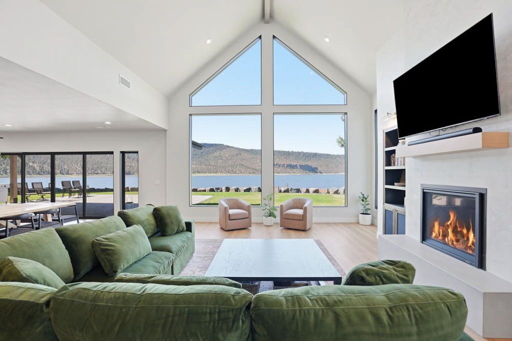 A modern living room with a large window, a fireplace, and a flat-screen TV.